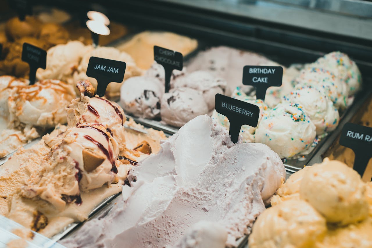 A colorful selection of ice creams showcases diverse flavors like blueberry and birthday cake in a display cabinet.